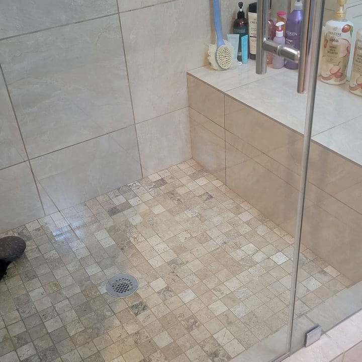 Glass walk-in shower with beige tile after cleaning by Meza Cleaning Service LLC in Las Vegas