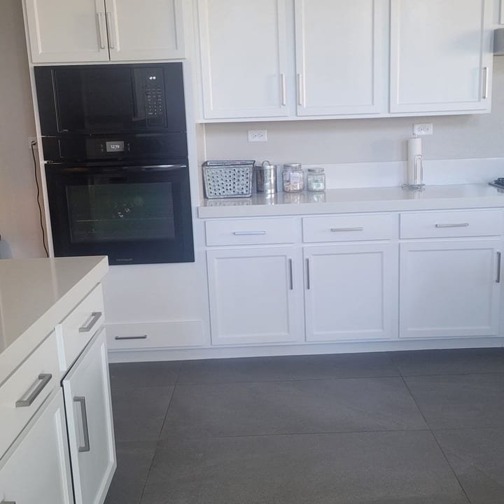 White kitchen cabinets, wall oven and countertops after a house cleaning visit