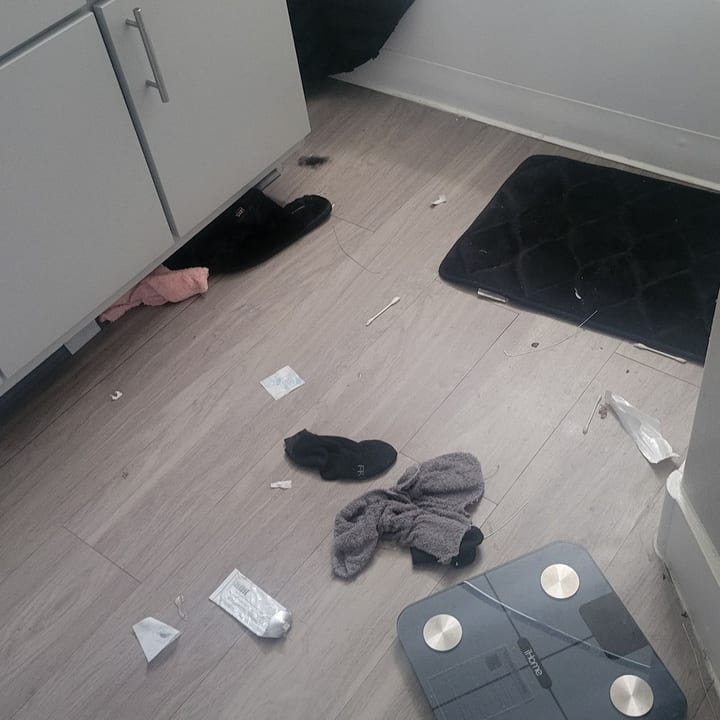 Bedroom floor before cleaning, with clothes and debris scattered across it