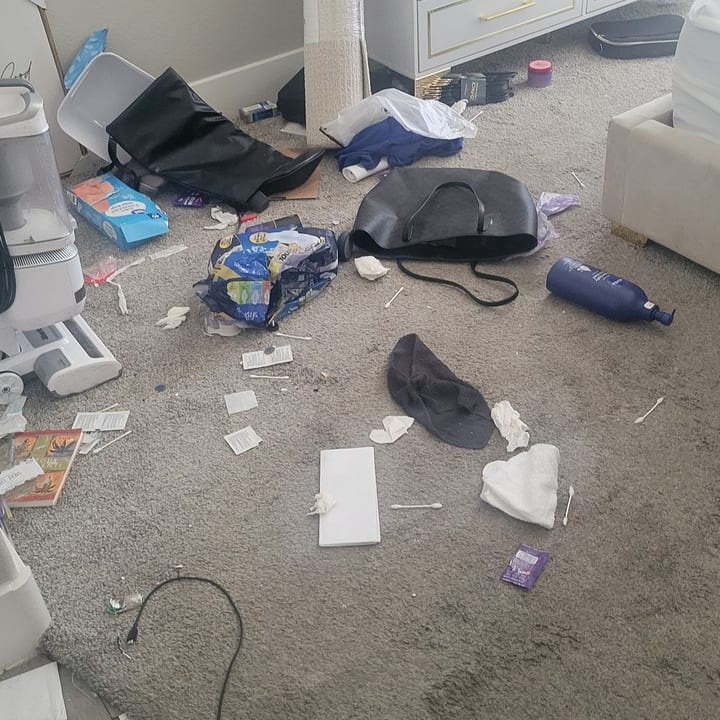 Bedroom carpet before cleaning, covered in clutter and packaging